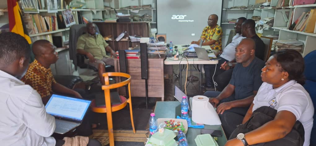 Meeting in an office with a projector screen and laptops in Ghana